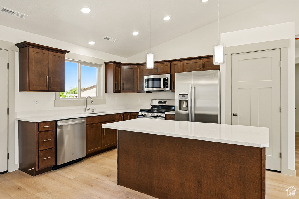 Kitchen featuring stainless steel appliances, a sink, light wood finished floors, dark brown cabinets, and lofted ceiling