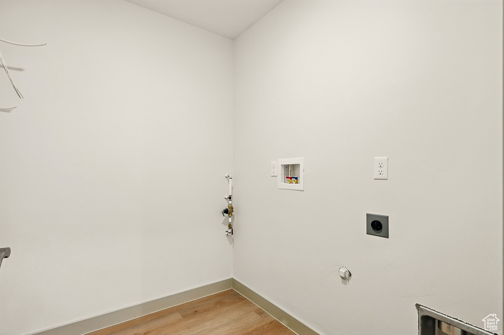 Washroom featuring hookup for a washing machine, gas dryer hookup, light wood finished floors, baseboards, and electric dryer hookup