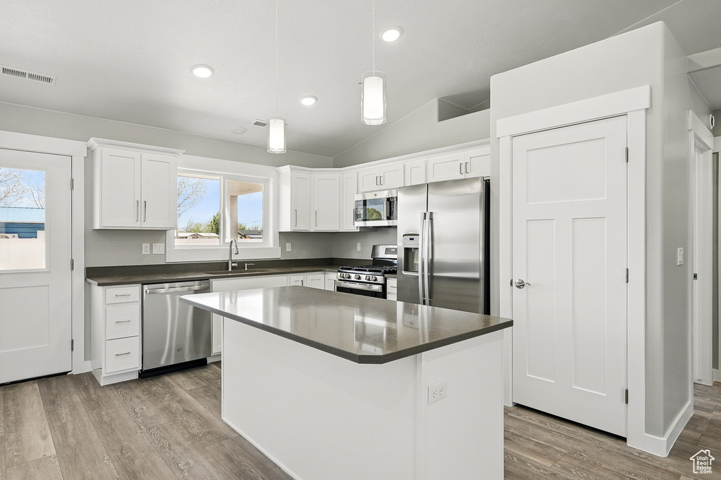Kitchen featuring visible vents, appliances with stainless steel finishes, dark countertops, a sink, and white cabinetry