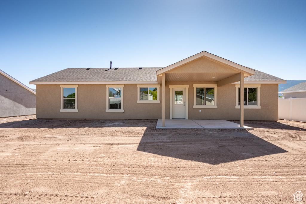 Back of house featuring a patio area, stucco siding, and a shingled roof