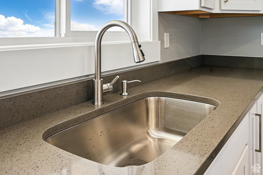 Details featuring dark stone counters, white cabinetry, and a sink