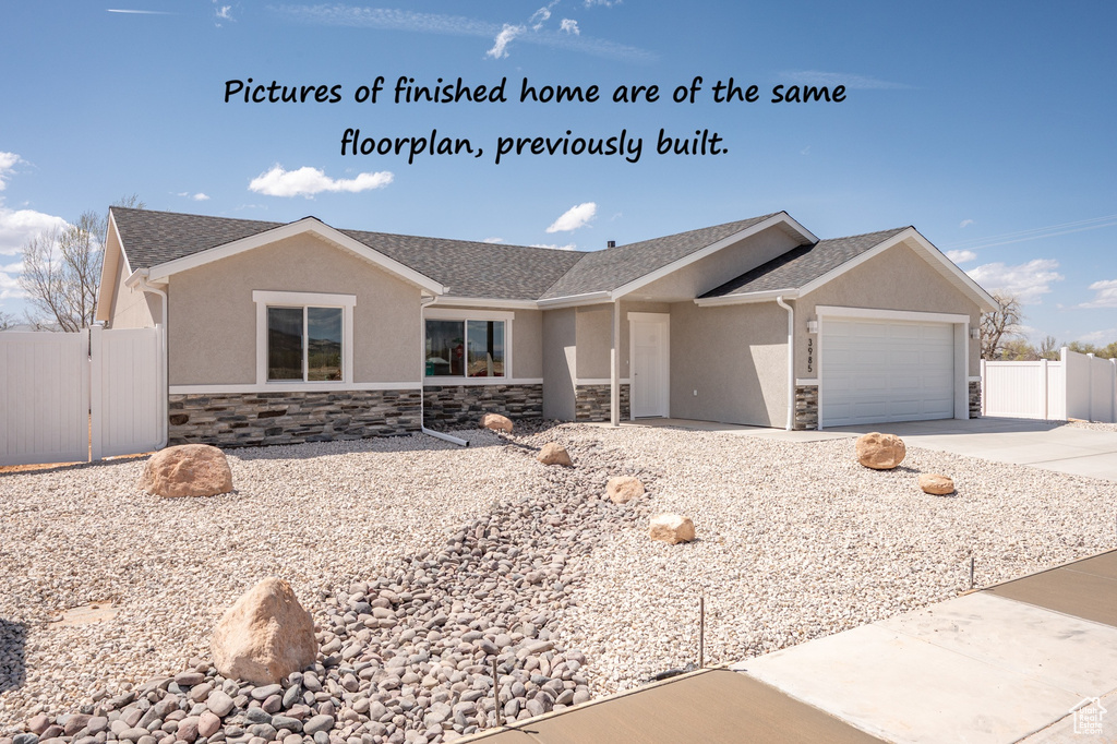 Ranch-style house featuring fence, an attached garage, stucco siding, and stone siding