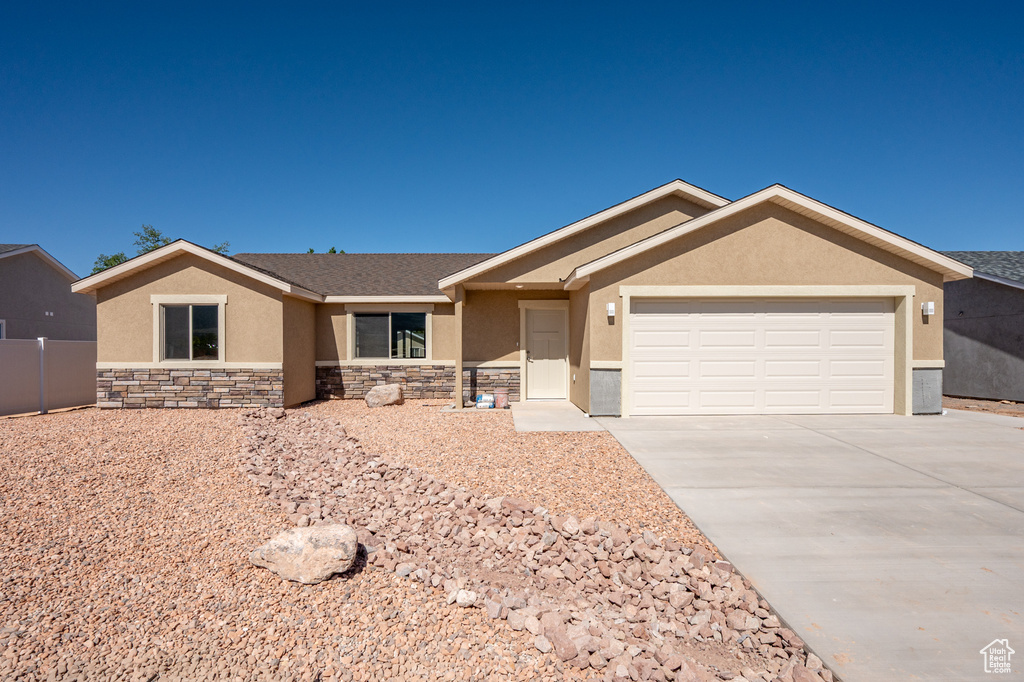 Ranch-style home with stucco siding, concrete driveway, an attached garage, and stone siding