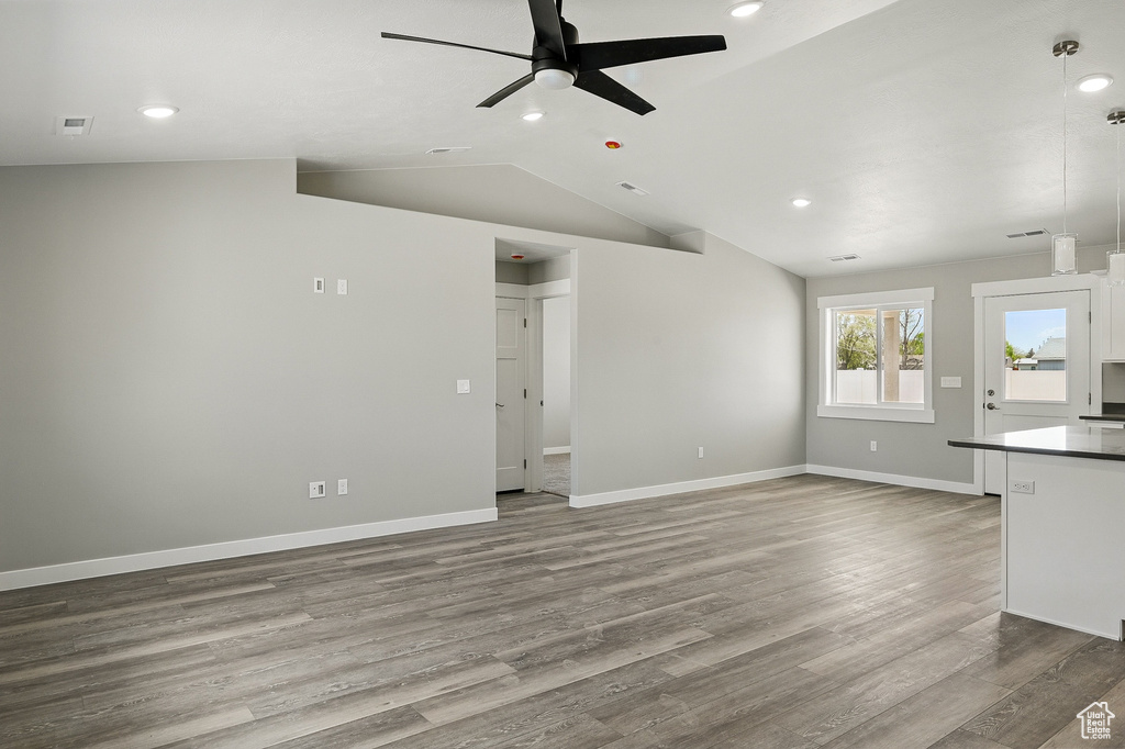 Unfurnished living room with ceiling fan, recessed lighting, baseboards, wood finished floors, and lofted ceiling