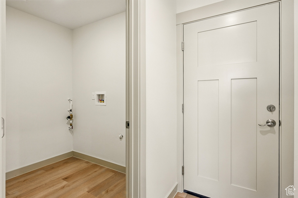 Laundry room with washer hookup, light wood-type flooring, and baseboards