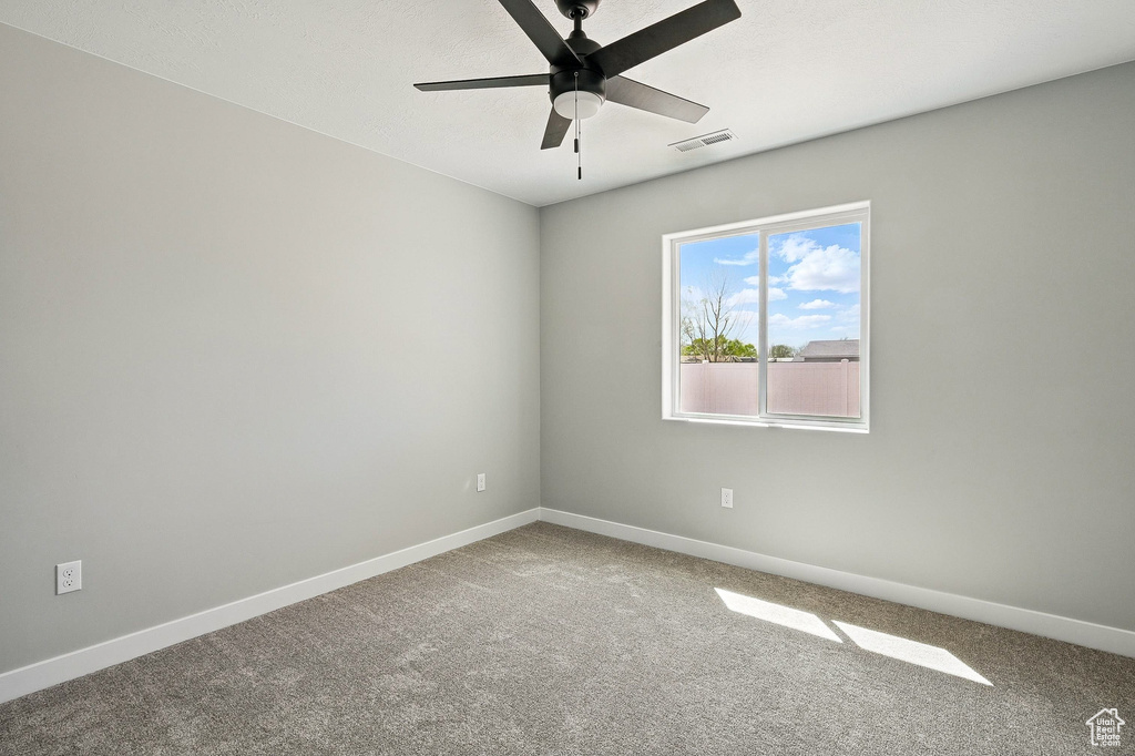 Carpeted empty room with baseboards, a ceiling fan, and visible vents