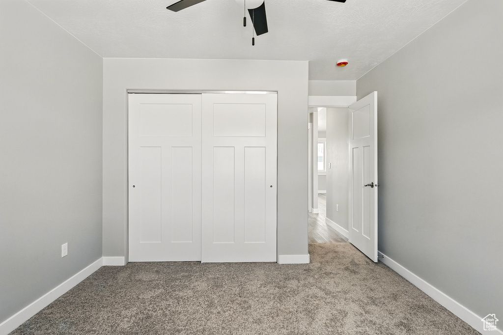 Unfurnished bedroom featuring carpet floors, a ceiling fan, baseboards, and a closet