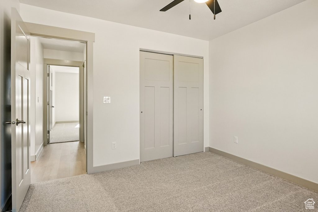 Unfurnished bedroom with light carpet, a closet, baseboards, and ceiling fan