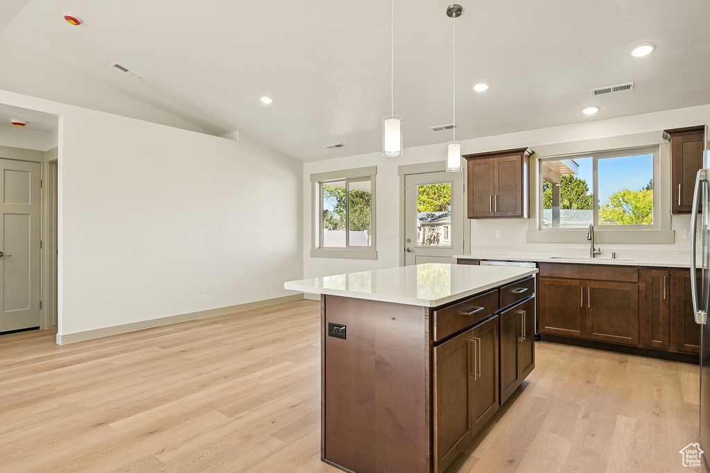 Kitchen with a sink, a center island, light wood finished floors, healthy amount of natural light, and lofted ceiling