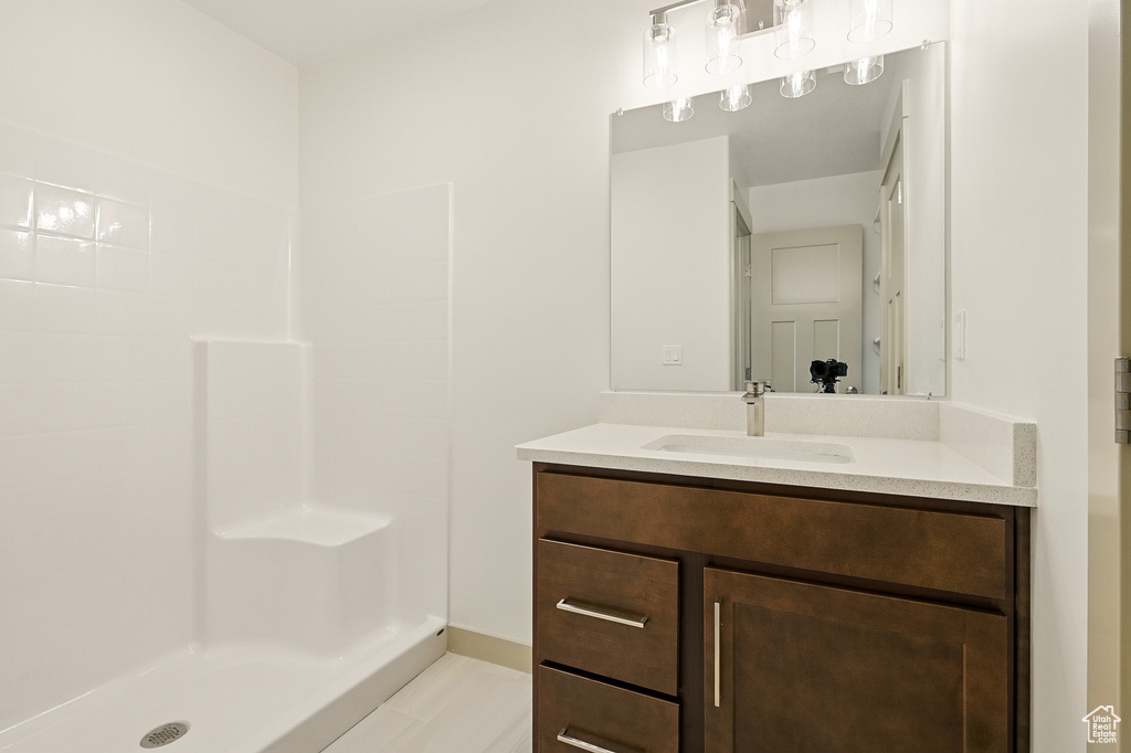 Full bathroom with vanity, a shower, and baseboards