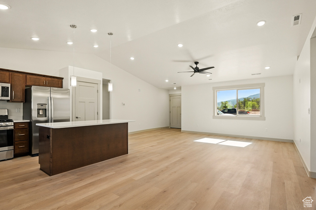 Kitchen featuring stainless steel appliances, a kitchen island, light countertops, a ceiling fan, and dark brown cabinets