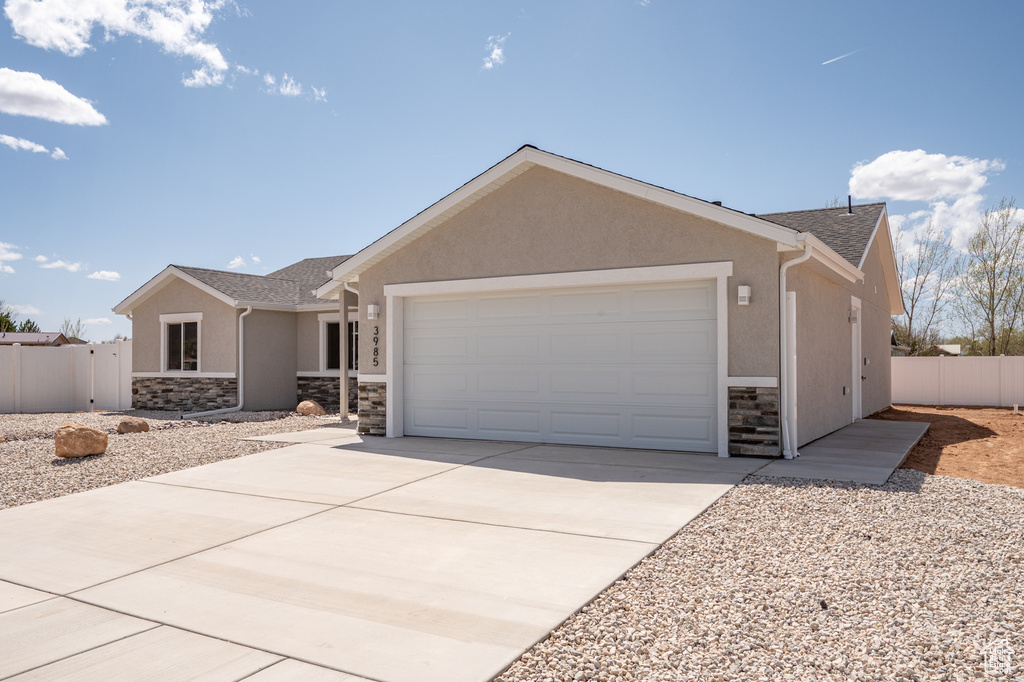 Single story home with a garage, stucco siding, and stone siding