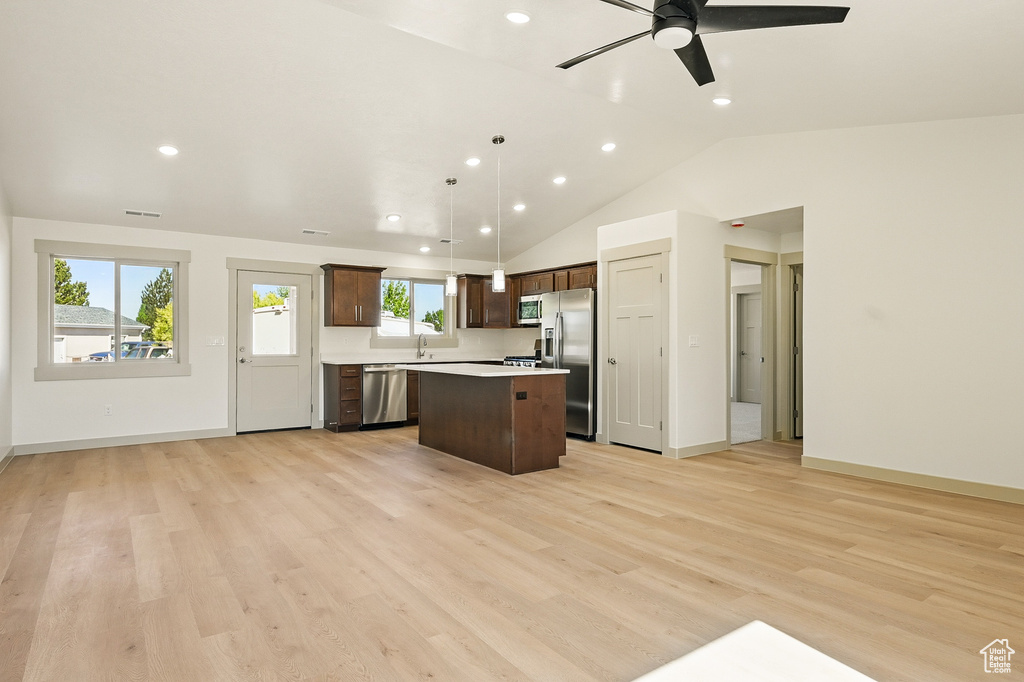 Kitchen featuring stainless steel appliances, a center island, open floor plan, dark brown cabinetry, and light countertops
