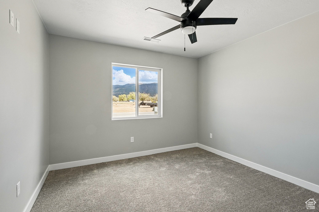 Empty room featuring a ceiling fan, baseboards, visible vents, and carpet