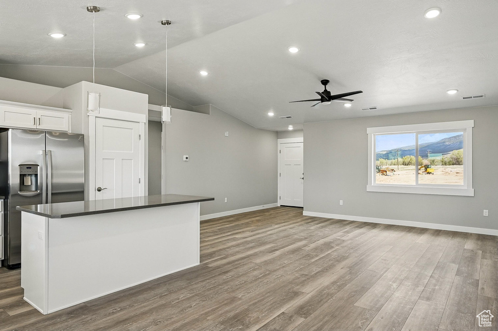 Kitchen featuring dark countertops, stainless steel fridge with ice dispenser, ceiling fan, and wood finished floors