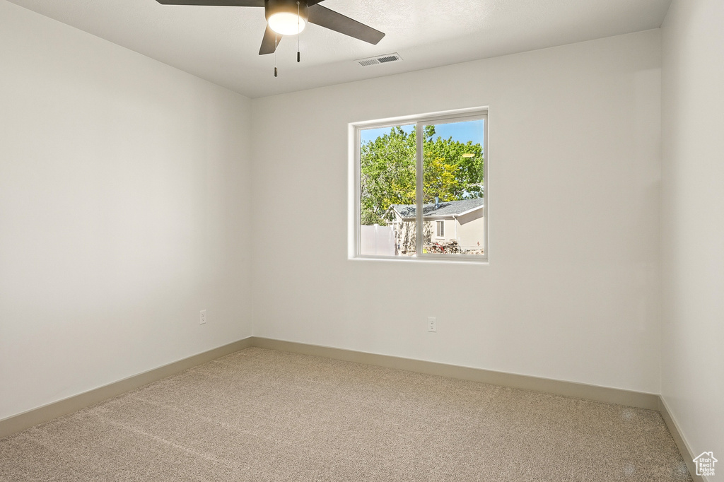 Carpeted spare room with ceiling fan and baseboards