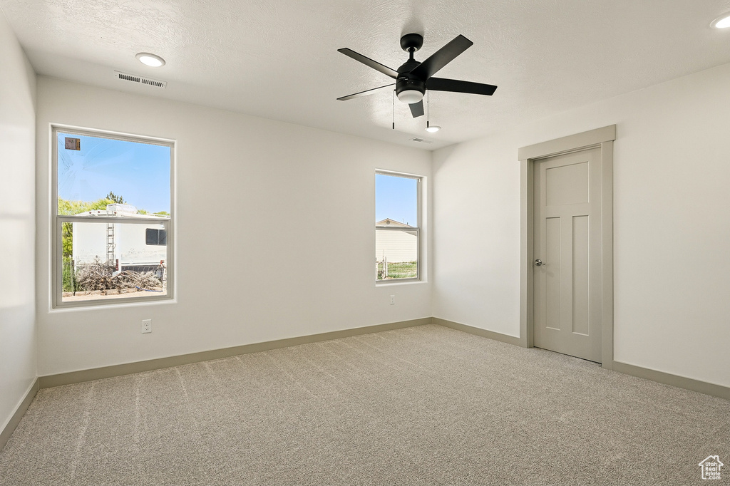 Carpeted empty room featuring baseboards and a ceiling fan