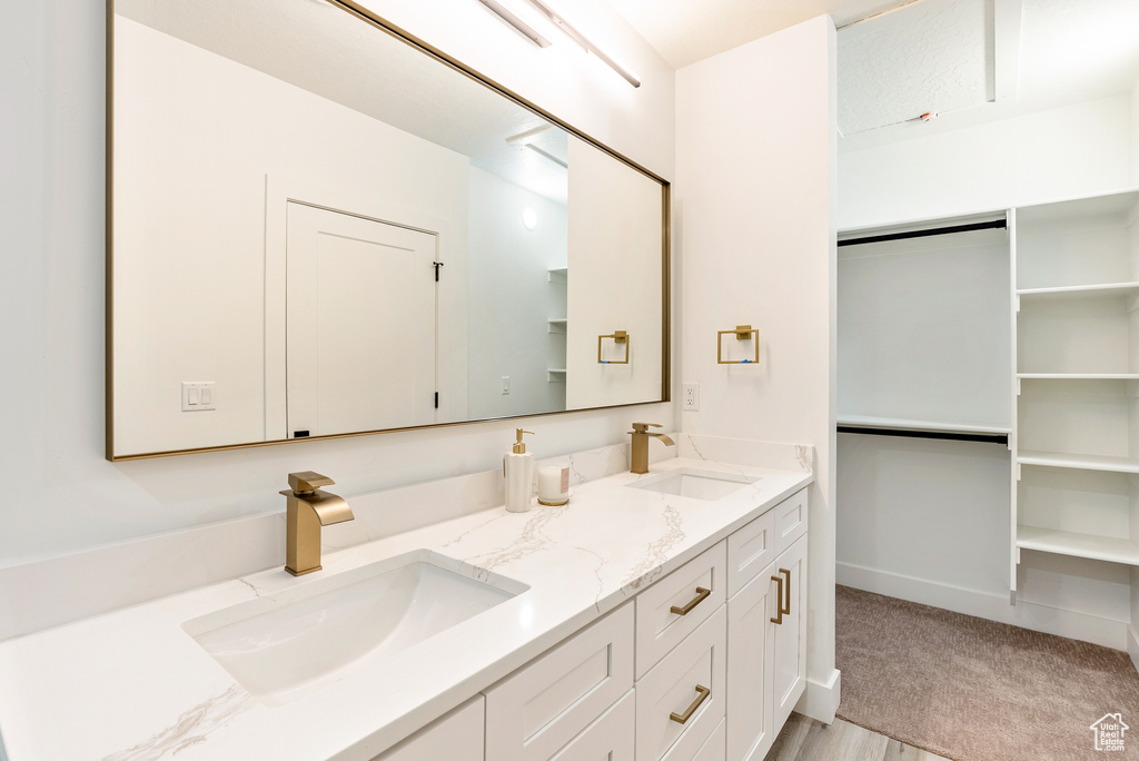 Full bath with double vanity, baseboards, and a sink