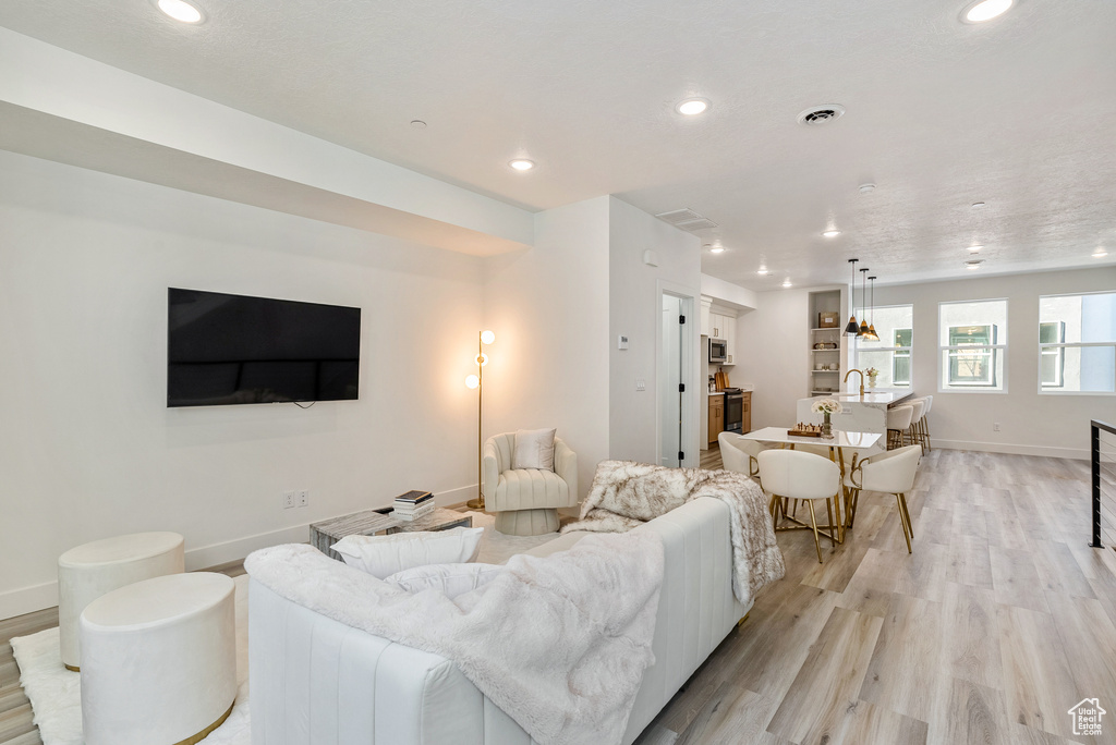 Living area featuring baseboards, visible vents, light wood-style flooring, and recessed lighting