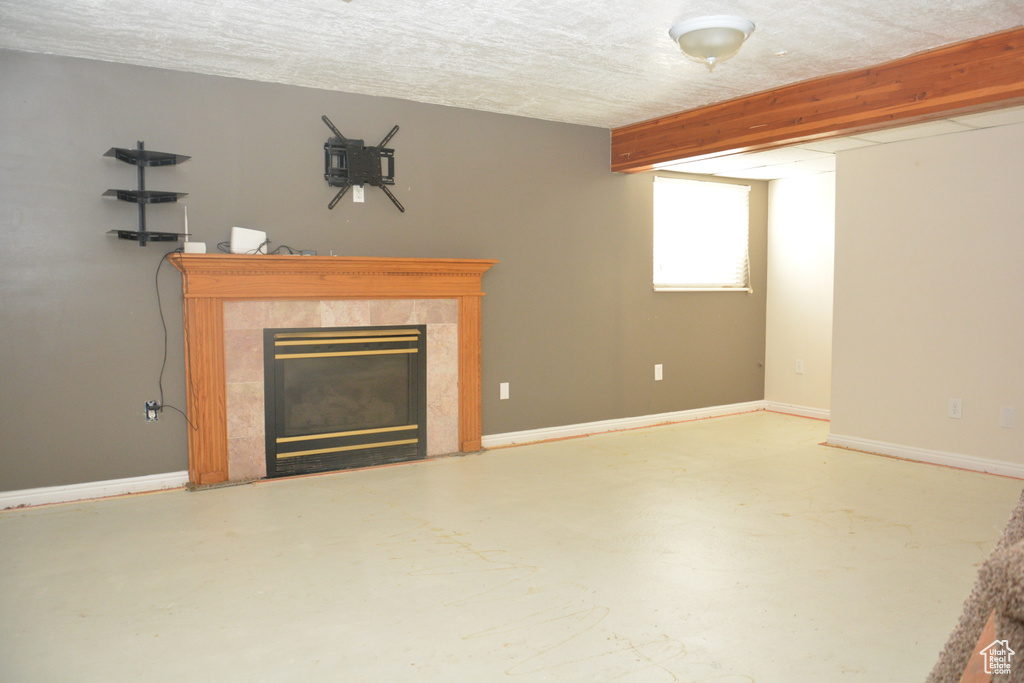 Unfurnished living room with baseboards, a tile fireplace, and finished concrete floors