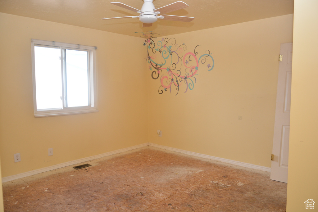 Empty room with baseboards, visible vents, and a ceiling fan