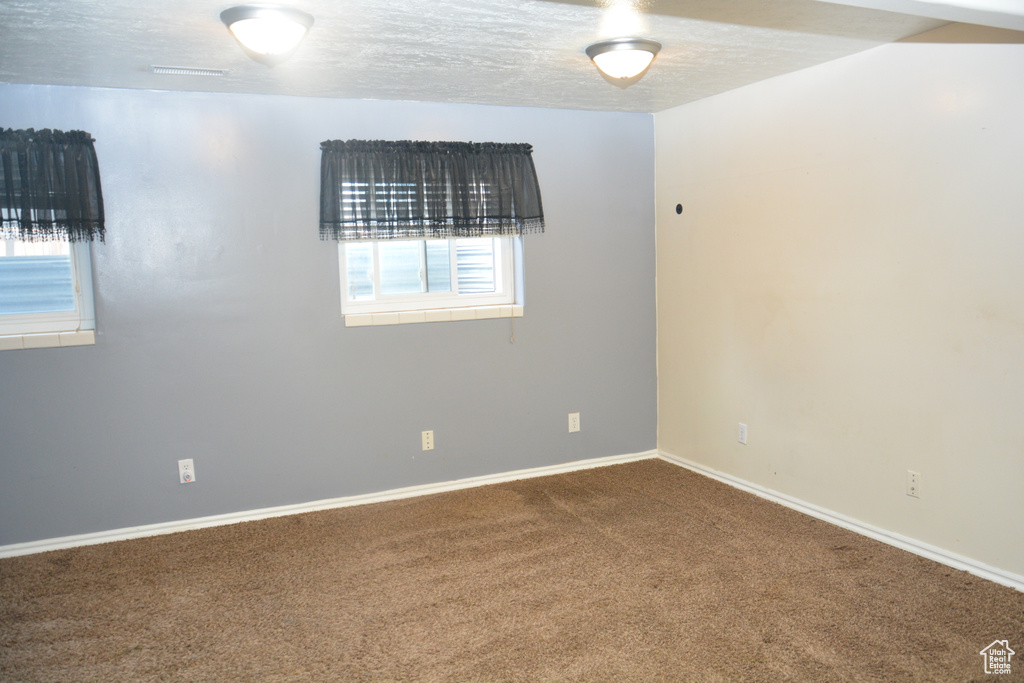 Carpeted spare room with a textured ceiling and baseboards