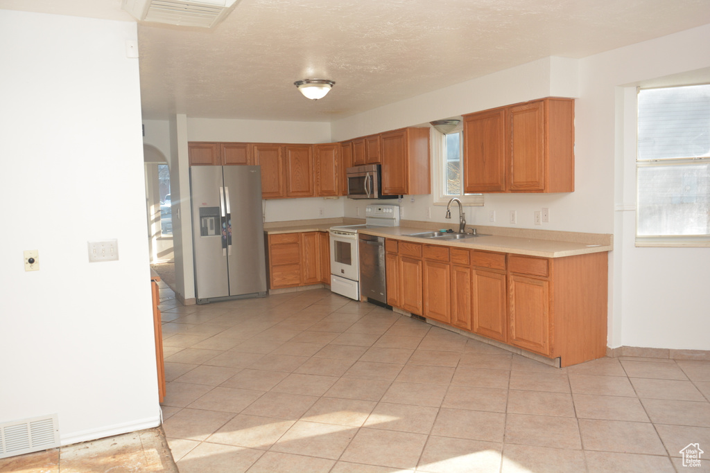 Kitchen with light countertops, a sink, appliances with stainless steel finishes, light tile patterned floors, and visible vents