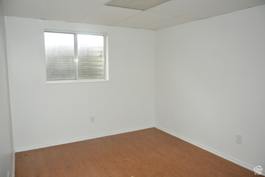 Empty room with a paneled ceiling, baseboards, and wood finished floors