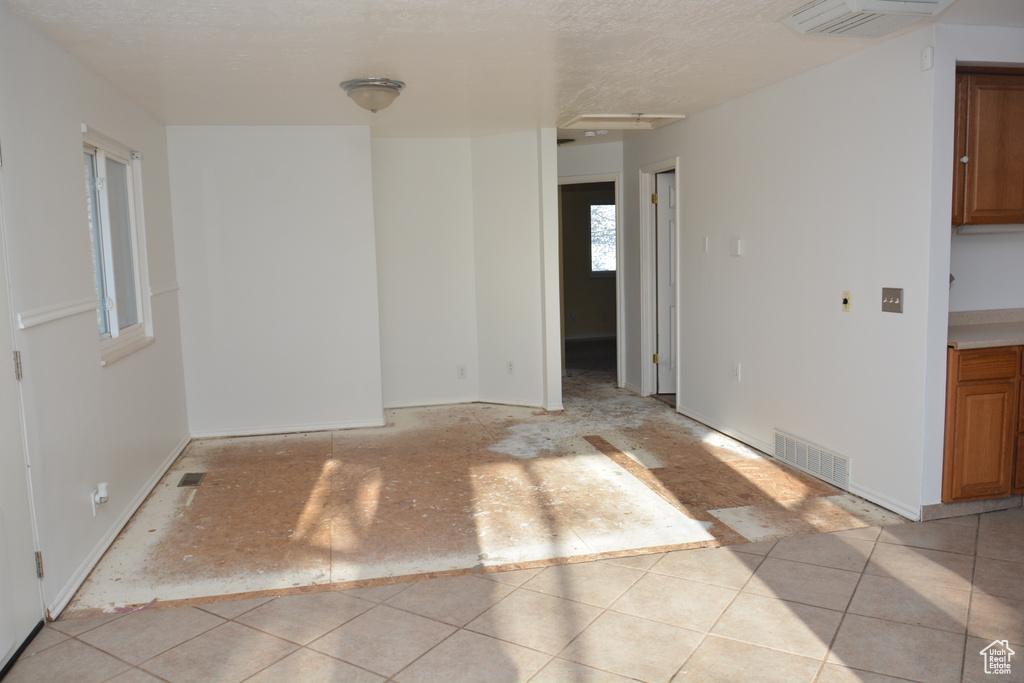 Unfurnished room featuring light tile patterned flooring, a textured ceiling, and visible vents