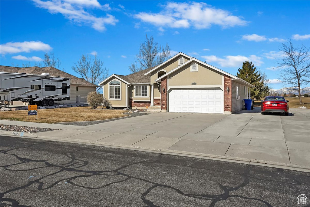 View of front of house with a garage, brick siding, driveway, and stucco siding