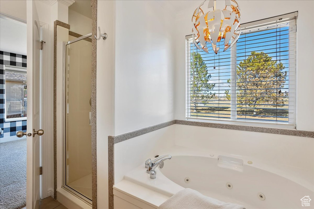 Bathroom featuring a chandelier, a shower stall, and a tub with jets