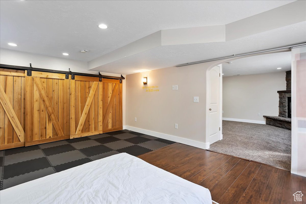 Bedroom featuring arched walkways, a barn door, a fireplace, and baseboards
