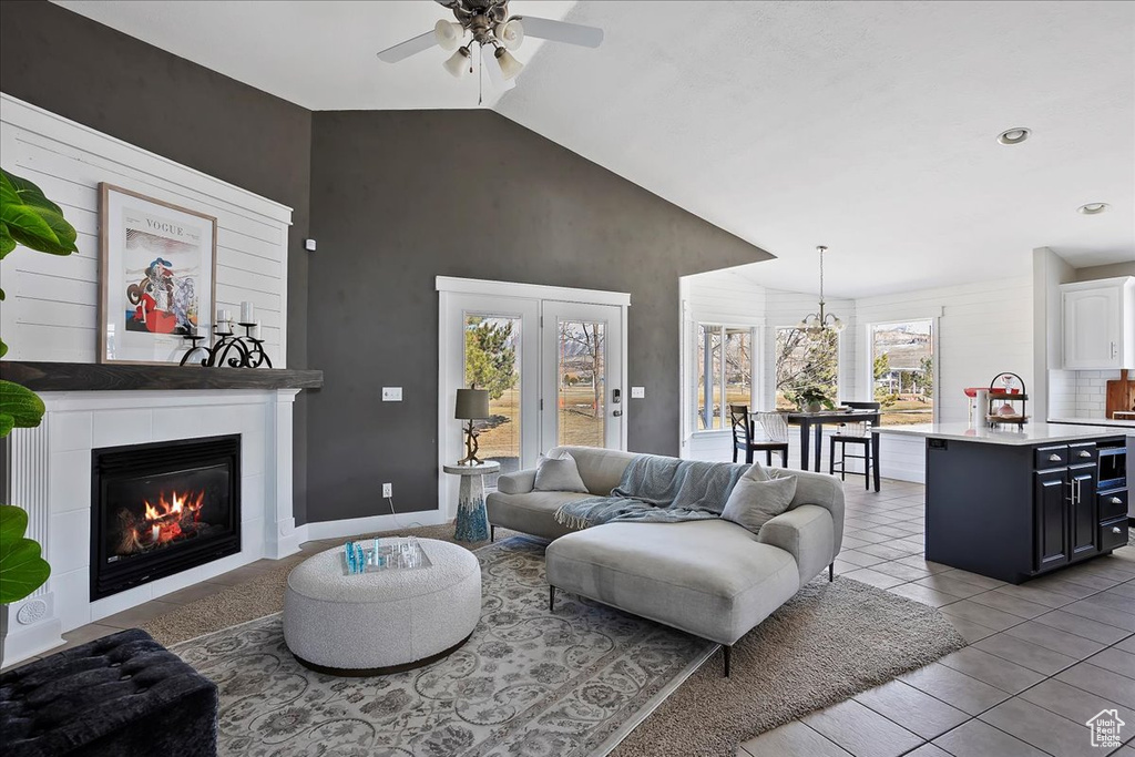 Living room with ceiling fan, a tile fireplace, vaulted ceiling, and light tile patterned floors