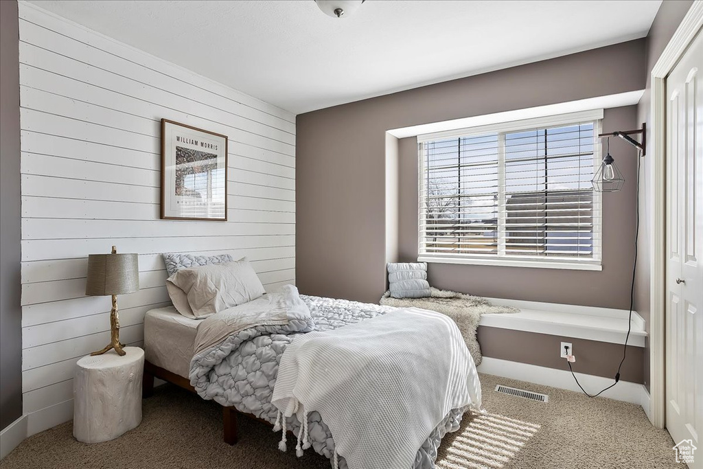 Bedroom featuring carpet floors, visible vents, and wooden walls