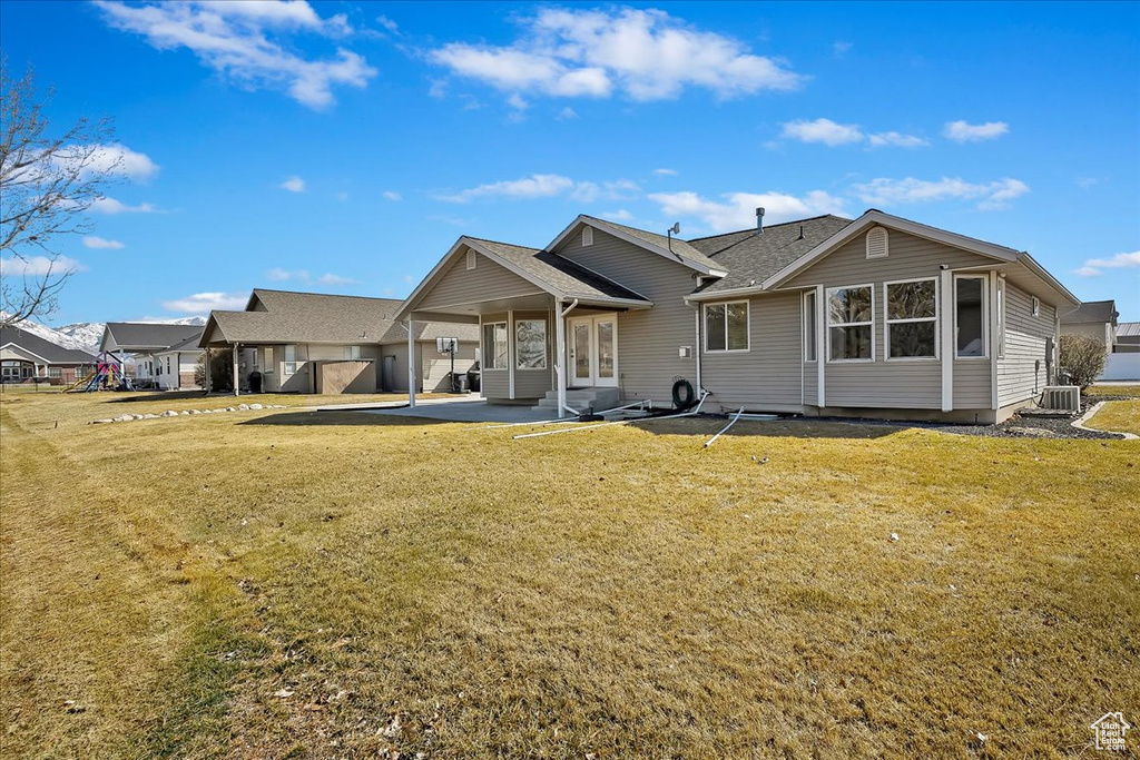 Back of house with a patio, central air condition unit, a yard, french doors, and a residential view