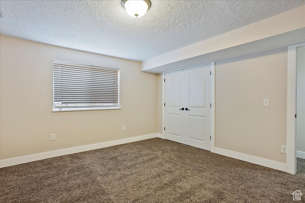 Unfurnished bedroom featuring a closet, carpet flooring, a textured ceiling, and baseboards