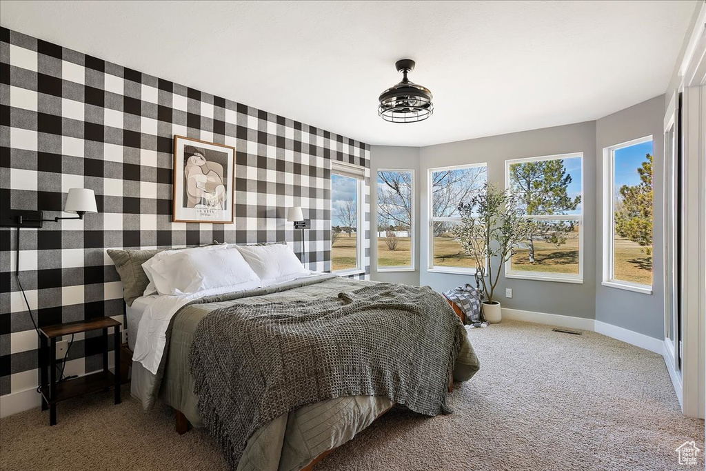 Bedroom with light colored carpet, an accent wall, visible vents, baseboards, and wallpapered walls