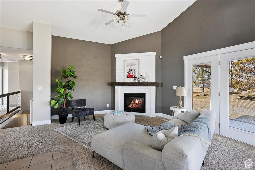 Carpeted living area with ceiling fan, baseboards, and a glass covered fireplace