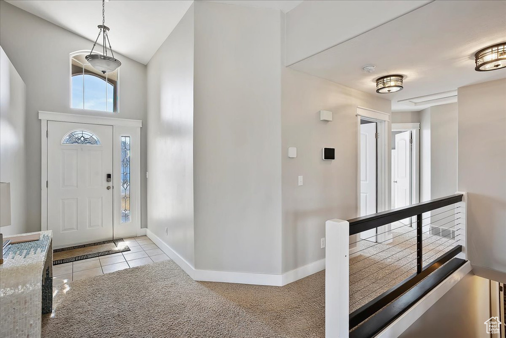 Foyer with light colored carpet, a towering ceiling, baseboards, and light tile patterned floors