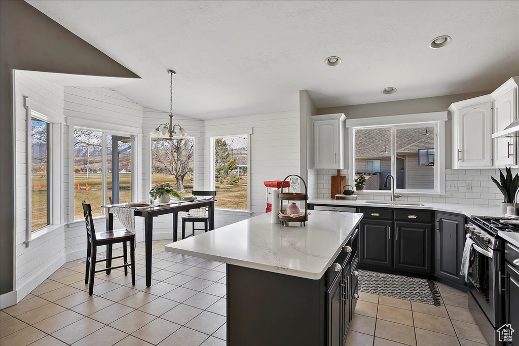 Kitchen featuring light tile patterned flooring, white cabinetry, a sink, gas range, and dark cabinets