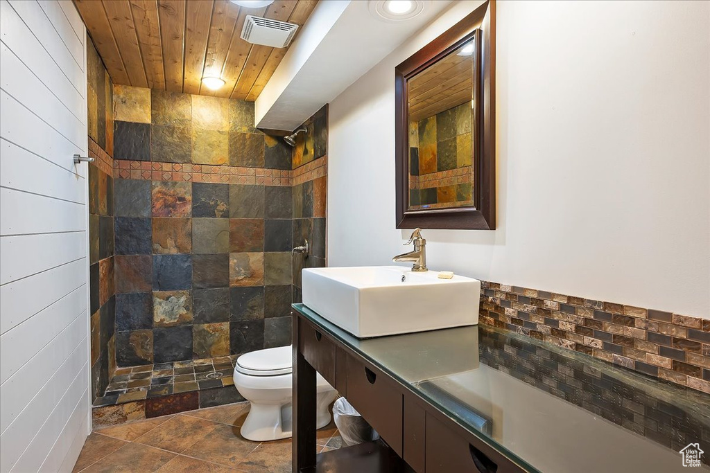 Full bathroom featuring visible vents, toilet, vanity, wooden ceiling, and tiled shower