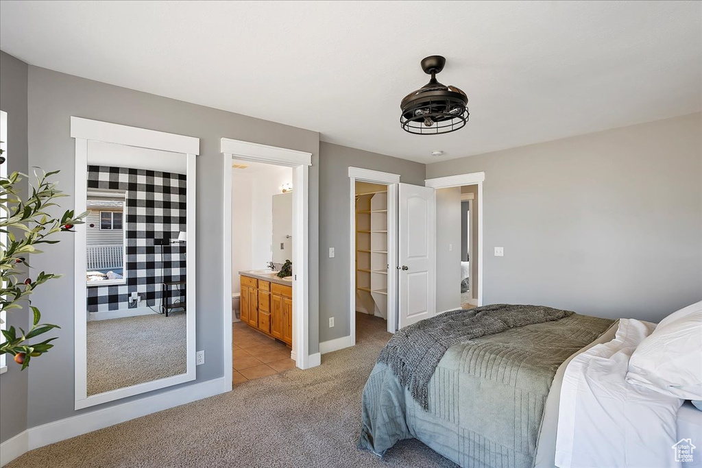 Bedroom featuring light carpet, ensuite bath, a spacious closet, and baseboards