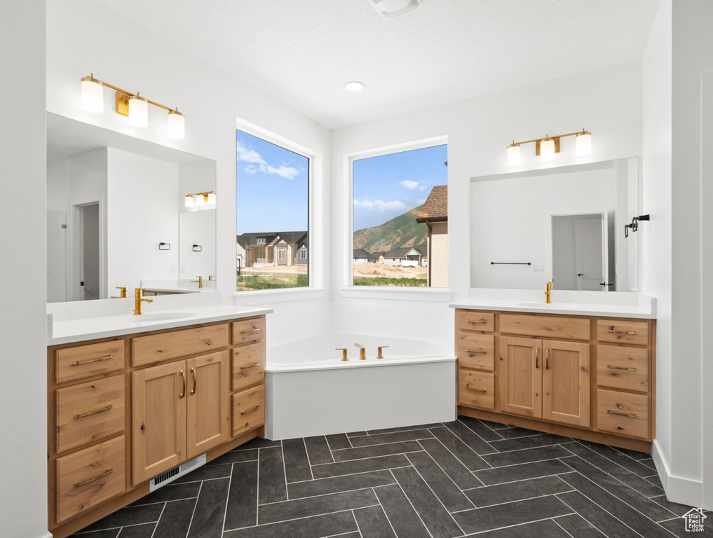 Bathroom featuring two vanities and a bath