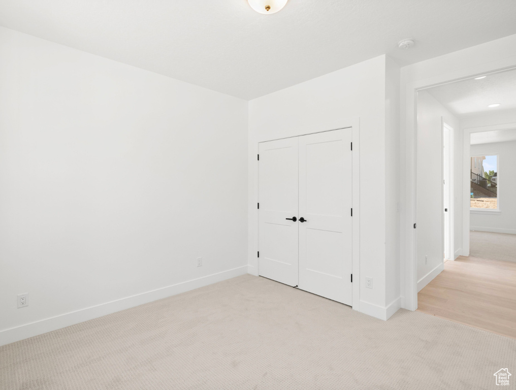Unfurnished bedroom with light colored carpet and a closet