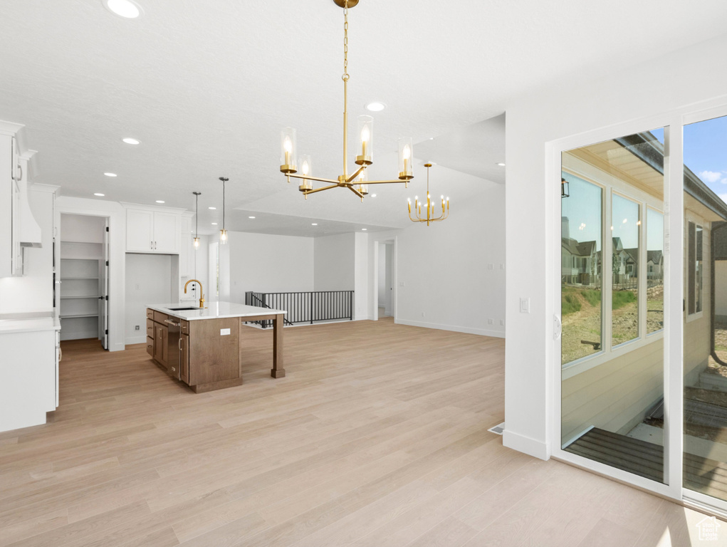 Kitchen with a chandelier, recessed lighting, light countertops, white cabinetry, and light wood-style flooring