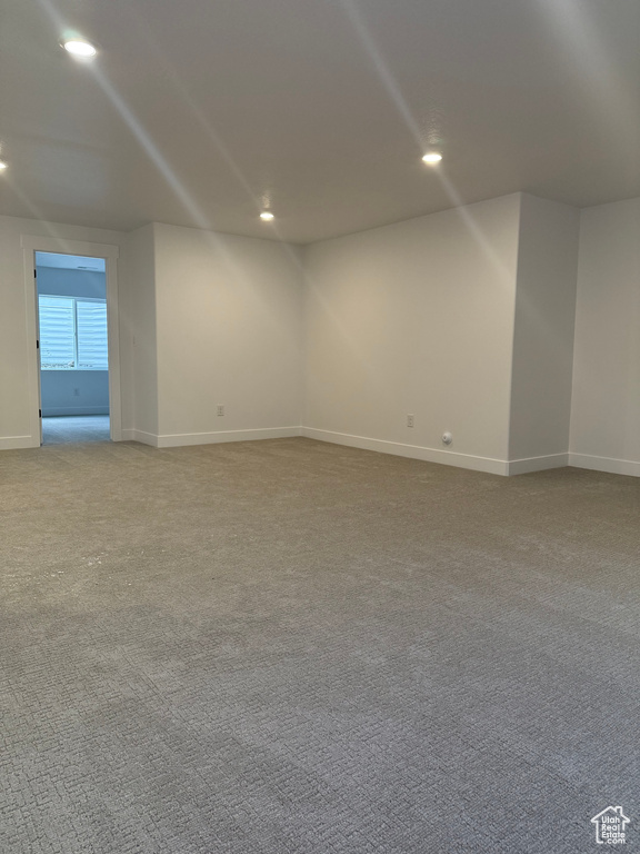 Empty room with baseboards, recessed lighting, and light colored carpet