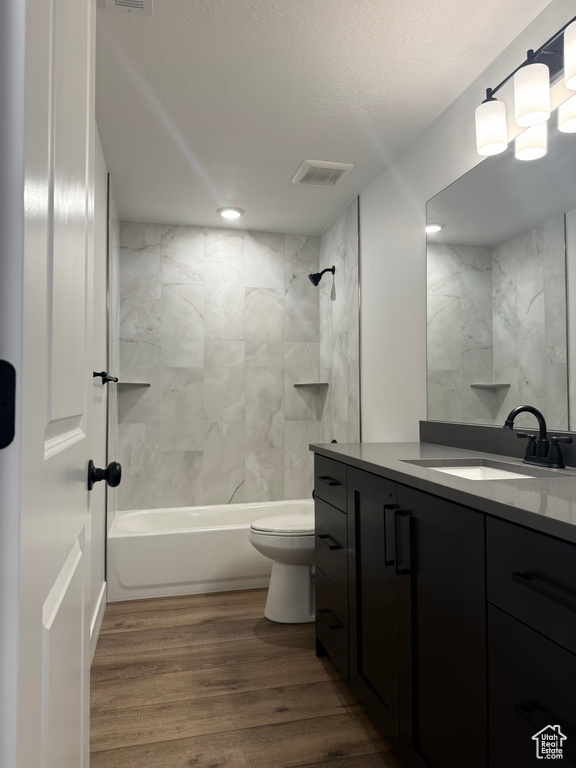 Full bathroom with visible vents, toilet, a textured ceiling, vanity, and wood finished floors