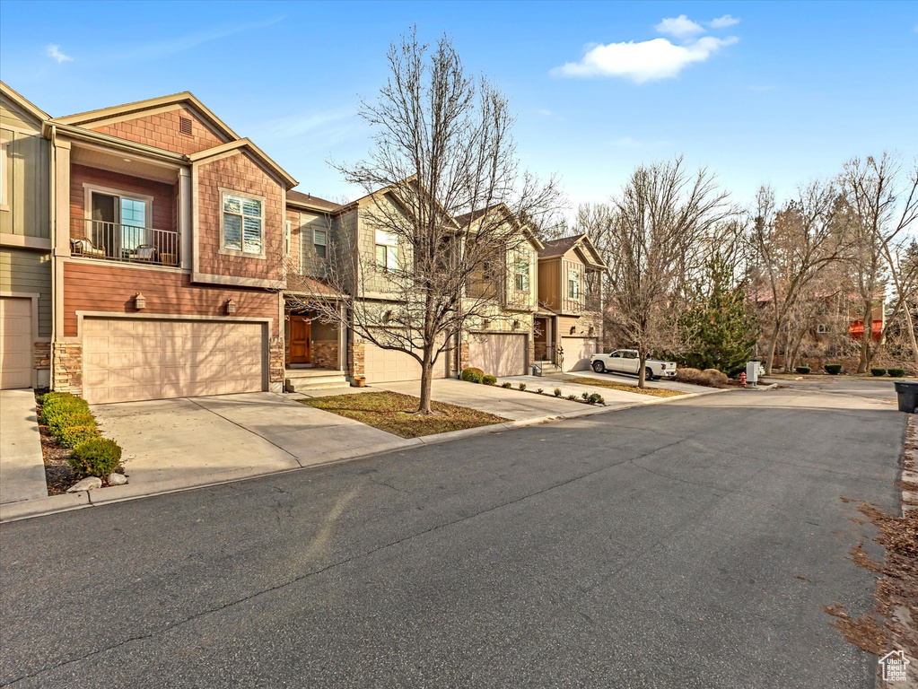 View of front of property with driveway, stone siding, an attached garage, and a residential view