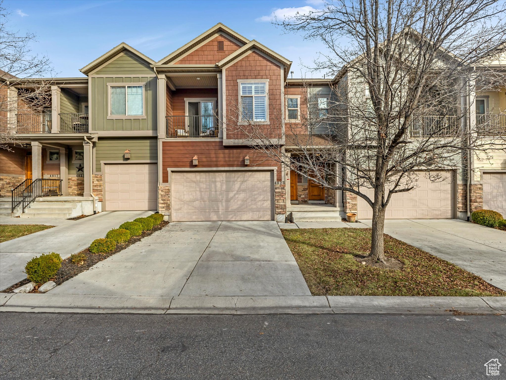 Townhome / multi-family property with board and batten siding, concrete driveway, a balcony, and a garage