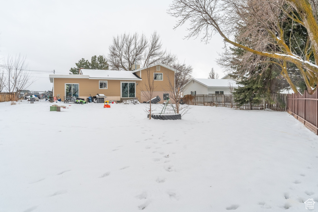Snow covered house with a fenced backyard